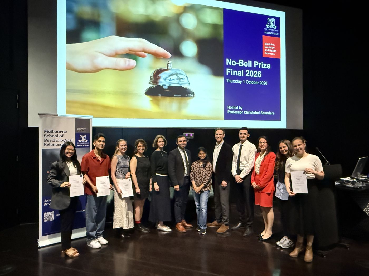Finalists and judges on stage under the No-Bell Prize Final 2026 slide