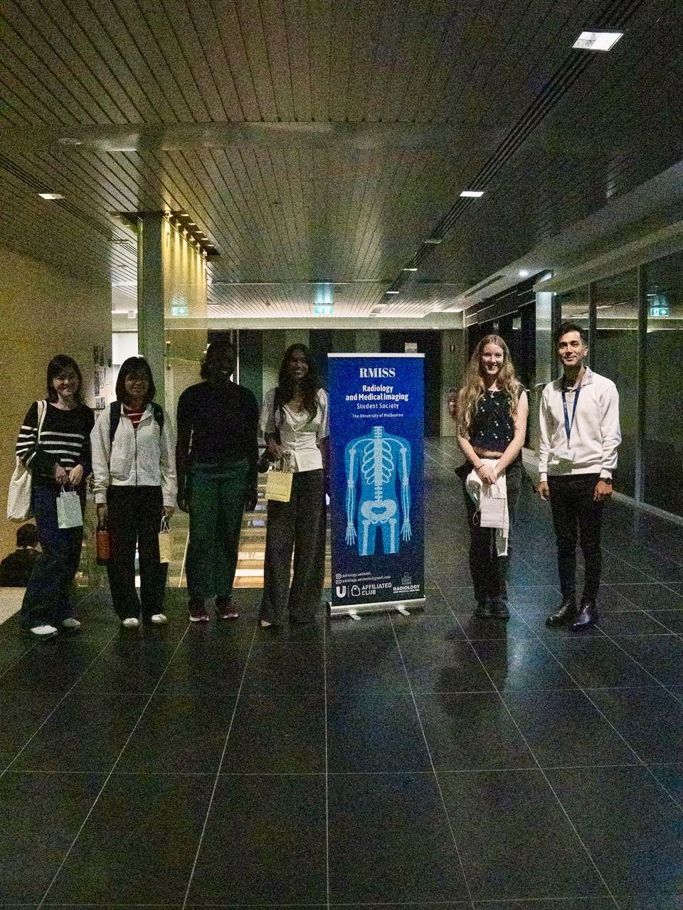 Ramin with students beside the RMISS banner